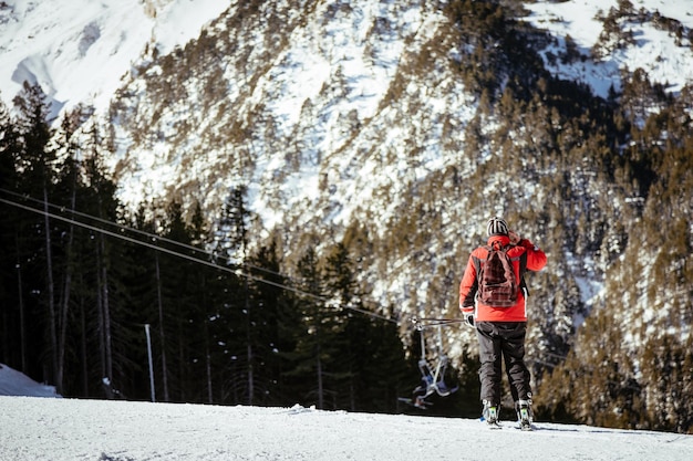 Vista traseira de um homem andando na montanha coberta de neve.