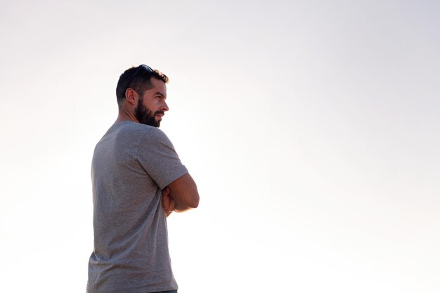 Vista traseira de um homem bonito com os braços cruzados com o céu no conceito de fundo de lazer e relaxe o espaço de cópia para texto