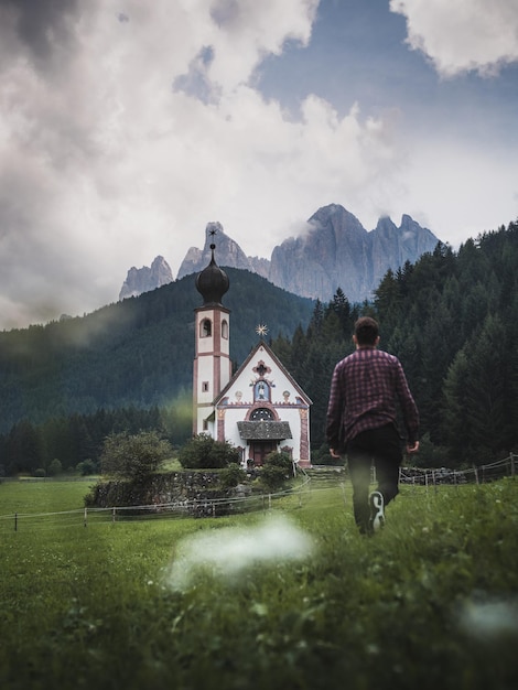 Vista traseira de um homem caminhando em direção à igreja em terra
