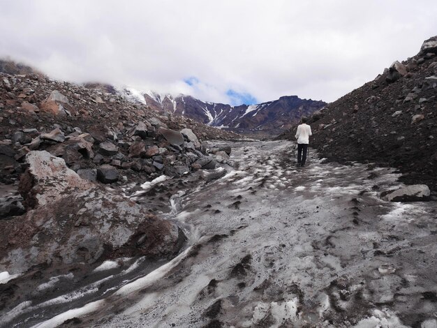 Vista traseira de um homem caminhando na montanha contra o céu nublado