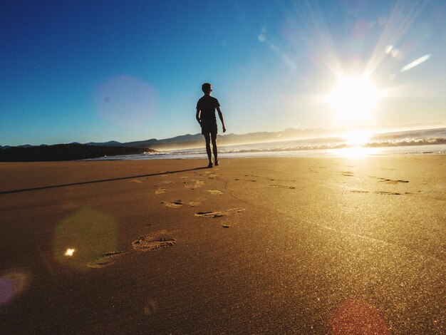 Foto vista traseira de um homem caminhando na praia contra o céu