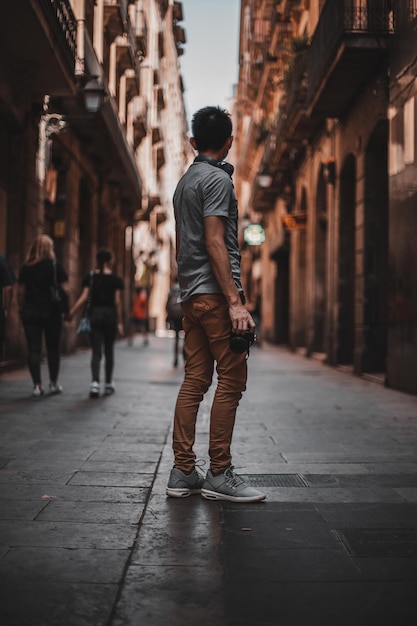 Foto vista traseira de um homem caminhando na rua em meio a edifícios