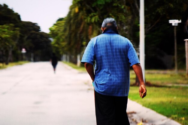 Vista traseira de um homem caminhando por uma trilha