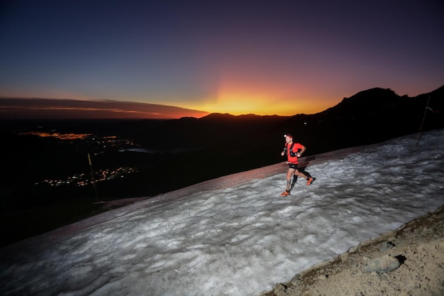 Foto vista traseira de um homem caminhando sobre uma paisagem coberta de neve durante o pôr do sol