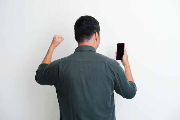 Vista traseira de um homem com o punho cerrado mostrando o gesto vencedor enquanto olha para o telefone