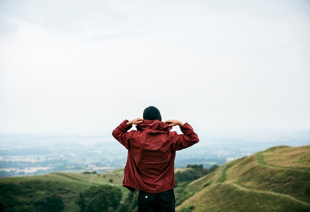 Foto vista traseira de um homem com uma jaqueta com capuz e paisagem natural