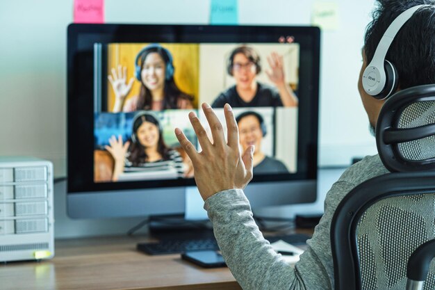 Foto vista traseira de um homem de negócios asiático dizendo olá com um colega de trabalho em equipe em videoconferência