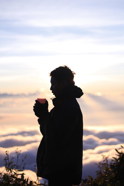 Foto vista traseira de um homem de pé contra o céu durante o pôr-do-sol