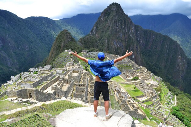 Foto vista traseira de um homem de pé em frente ao machu picchu