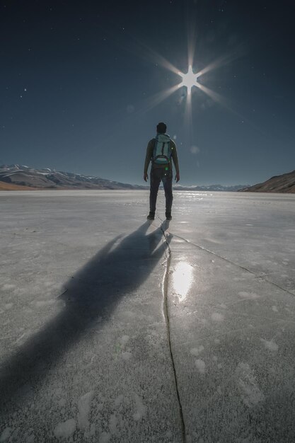 Foto vista traseira de um homem de pé em terra coberta de neve contra o céu