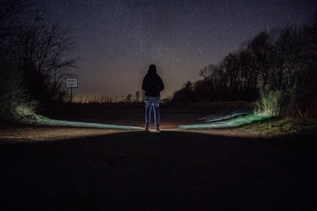 Foto vista traseira de um homem de pé na estrada à noite