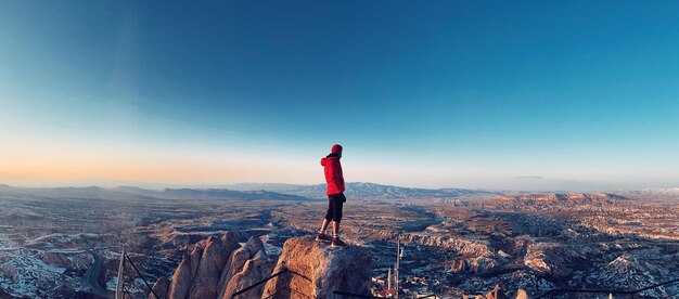 Foto vista traseira de um homem de pé na montanha contra o céu azul