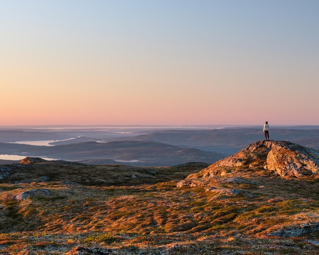 Foto vista traseira de um homem de pé na montanha durante o pôr-do-sol