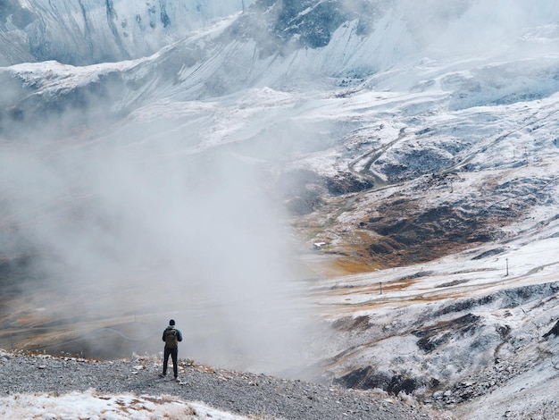 Vista traseira de um homem de pé na montanha durante o tempo nebuloso