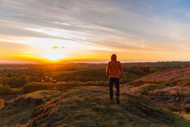 Vista traseira de um homem de pé na paisagem contra o céu ao pôr-do-sol