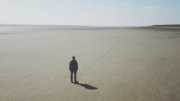 Foto vista traseira de um homem de pé na praia contra o céu