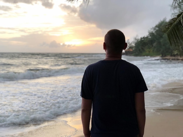 Vista traseira de um homem de pé na praia