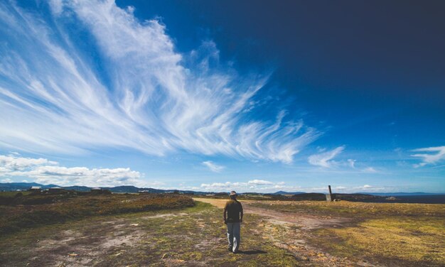 Vista traseira de um homem de pé no campo contra o céu