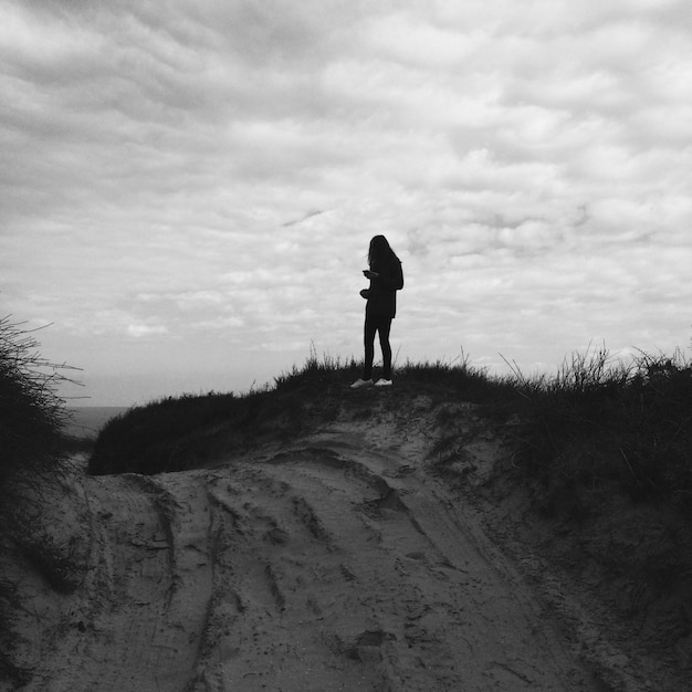 Vista traseira de um homem de silhueta caminhando na paisagem contra o céu