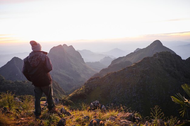 Foto vista traseira de um homem em silhueta de pé na montanha contra o céu durante o pôr do sol