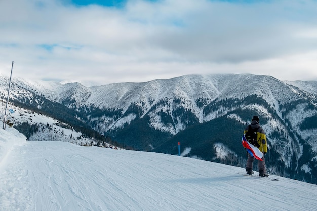Vista traseira de um homem esquiando em montanhas cobertas de neve contra o céu