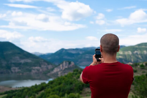 Vista traseira de um homem fotografando montanhas contra o céu