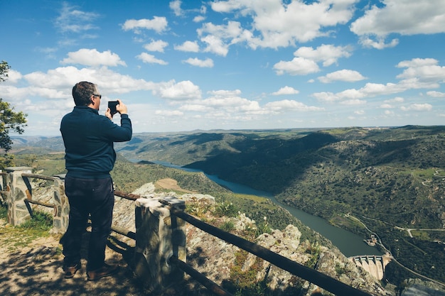 Foto vista traseira de um homem fotografando montanhas contra o céu