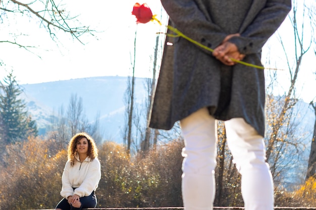 Foto vista traseira de um homem latino apaixonado escondendo uma rosa para sua namorada conceito de uma rosa para a namorada dia dos namorados
