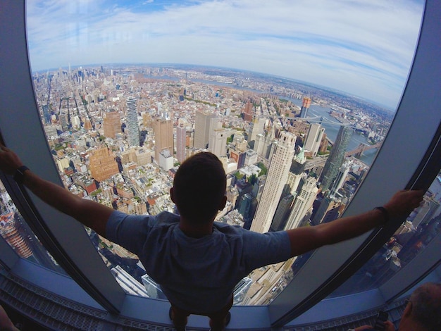 Foto vista traseira de um homem olhando para a paisagem da cidade através de uma janela