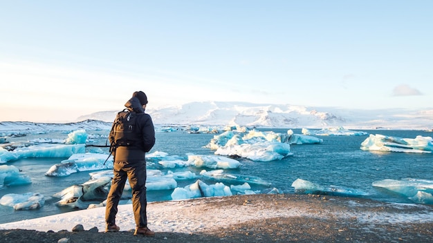 Foto vista traseira de um homem olhando para icebergs no mar