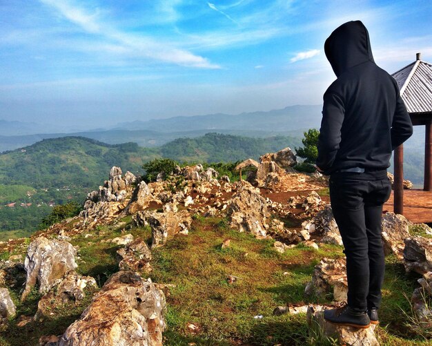 Foto vista traseira de um homem olhando para montanhas contra o céu