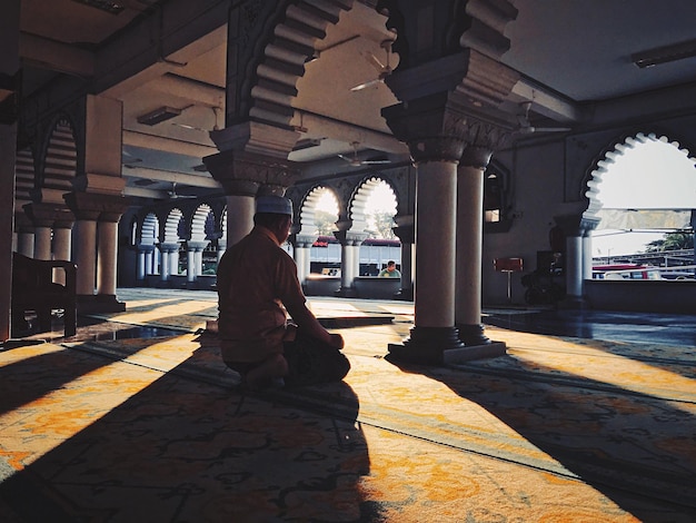 Vista traseira de um homem orando na mesquita