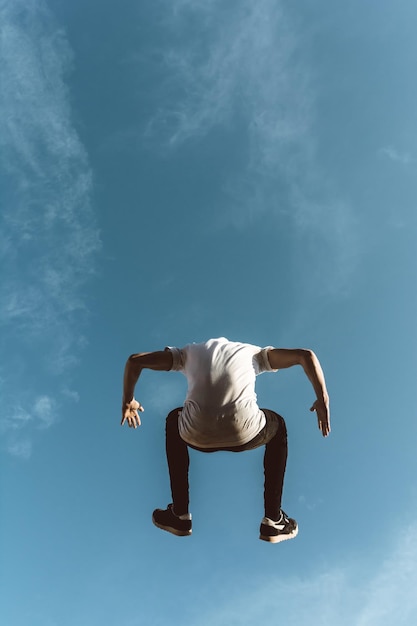 Foto vista traseira de um homem pulando contra o céu