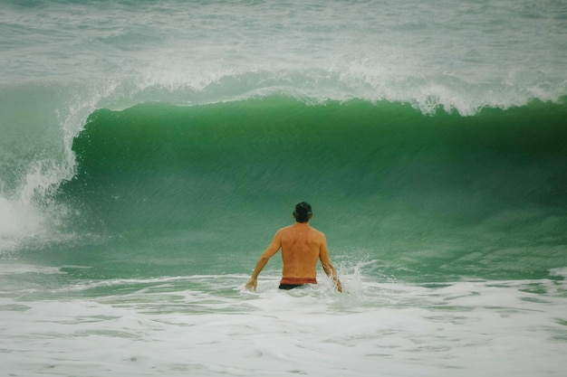 Foto vista traseira de um homem sem camisa de pé no mar