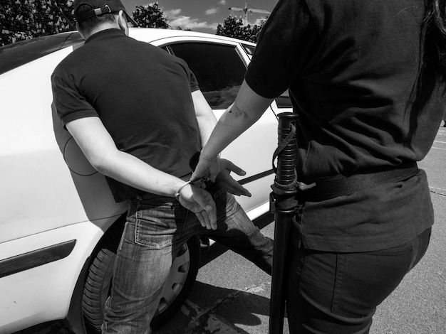 Vista traseira de um homem sendo preso por uma policial