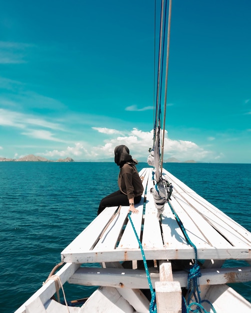 Vista traseira de um homem sentado em um barco no mar contra o céu