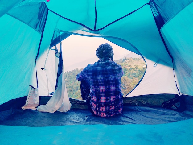 Foto vista traseira de um homem sentado na tenda