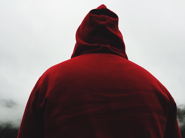 Foto vista traseira de um homem vestindo uma camisa com capuz vermelho durante o tempo nebuloso
