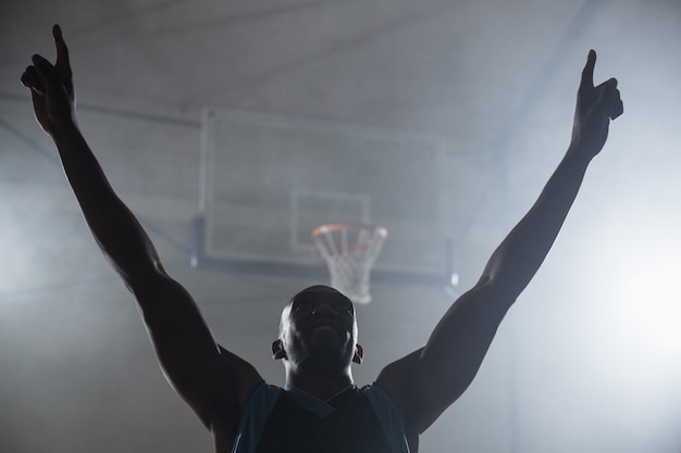 Vista traseira de um jogador de basquete com os braços no ar