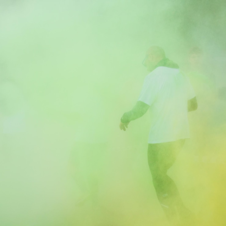 Foto vista traseira de um jovem caminhando na estrada em meio à pintura em pó verde