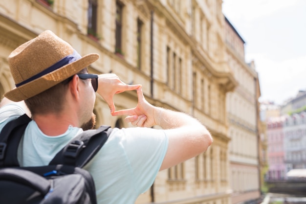 Vista traseira de um jovem turista tirando foto em frente à cidade