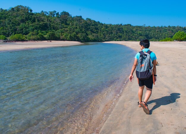 Foto vista traseira de um menino caminhando na praia