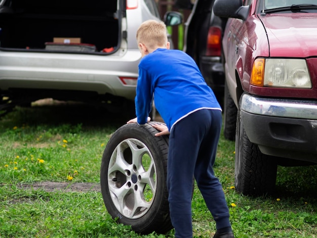 Vista traseira de um menino empurrando um pneu em terra