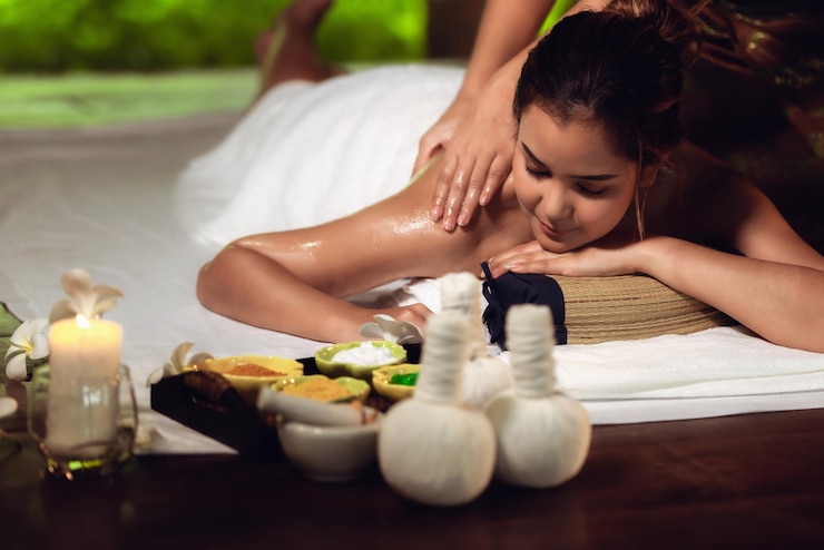 Foto vista traseira de um terapeuta massageando uma jovem mulher deitada em um spa