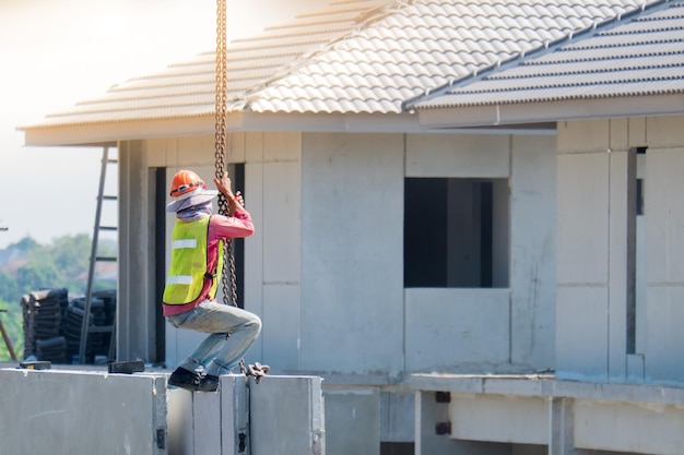 Vista traseira de um trabalhador pendurado em cadeias fora do canteiro de obras