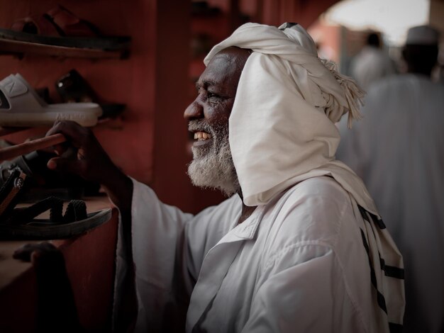 Vista traseira de um velho sudanês sorrindo e olhando para a janela