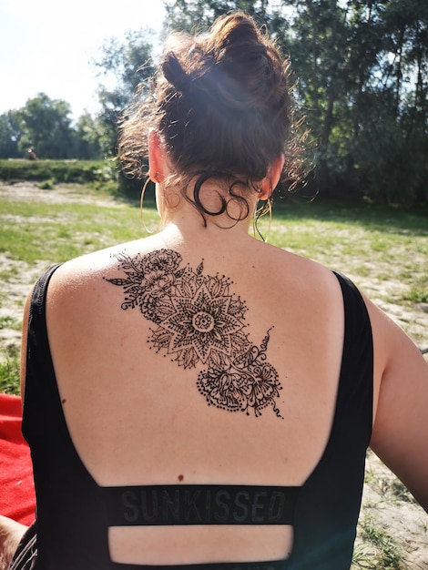 Foto vista traseira de uma adolescente com tatuagem de henna nas costas