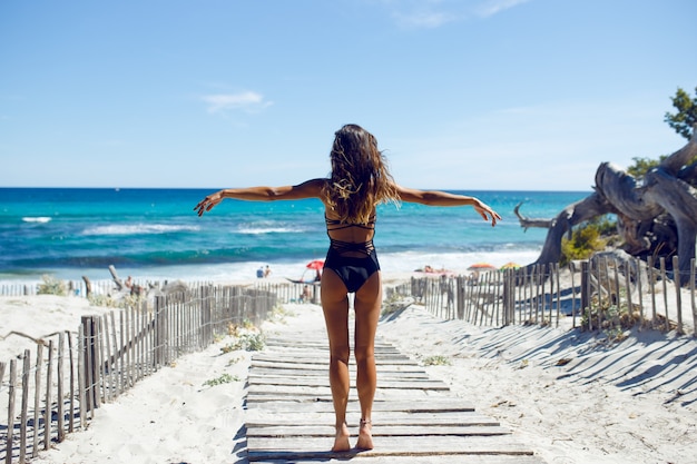 Vista traseira de uma bela jovem posando na praia. Oceano, praia, areia, fundo do céu. Férias na ilha da Córsega, França.