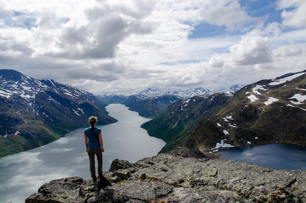 Vista traseira de uma caminhante olhando do topo de besseggen sobre o lago gjende e bessvatnet