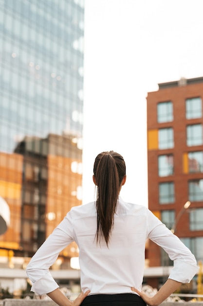 Vista traseira de uma empresária olhando para edifícios comerciais